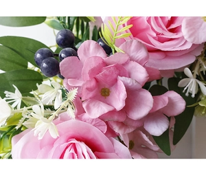 Macro shot of artificial pink roses, purple berries, and textured silk green leaves