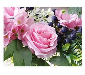 Close-up of artificial pink silk roses with blue berries and detailed green leaves