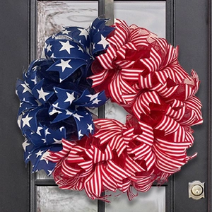 Close-up of July 4th patriotic wreath with red white and blue ribbons on dark front door