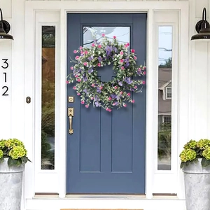 Spring artificial wildflower wreath with purple flowers and lush green leaves on front door