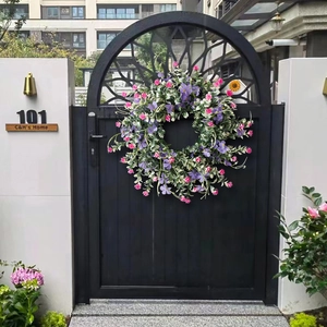 Spring wreath with purple wildflowers and green leaves on a black arched door