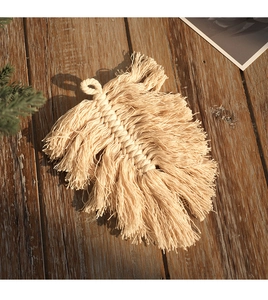 Detail of handmade off-white macrame leaf wall hanging on dark wood background