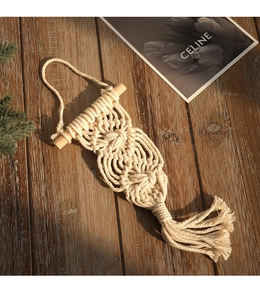 Detailed close-up of handmade macramé wall hanging with beige cotton rope and long tassels