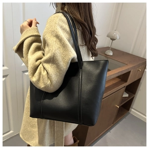 Detailed view of a black large capacity PU leather tote bag worn with a beige coat