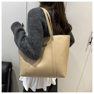 Close-up of a cream-colored leather tote bag styled with a grey sweater for daily wear
