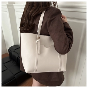 Détail du grand sac cabas crème avec sangle réglable et poche avant incurvée élégante