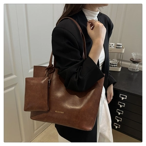 Close-up of vintage brown leather tote bag with matching mini pouch on a model
