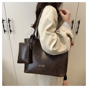 Detail shot of a dark brown vintage leather tote bag worn by a model in a minimalist setting