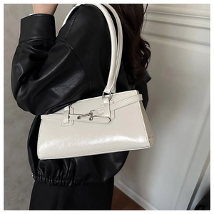 Gros plan du sac baguette crème brillant avec boucle mors en argent et anses longues