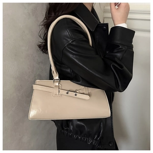 Detail of minimalist beige shoulder bag with decorative buckle on a black leather jacket
