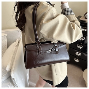 Detail of dark brown retro shoulder bag with silver buckle and eyelet belt on a model
