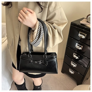 Détail du sac baguette en cuir noir synthétique avec boucle argentée vintage