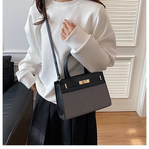 Detailed view of a black leather and grey woven handbag styled with a white sweatshirt