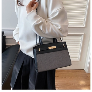 Close-up of stylish two-tone handbag featuring black leather and textured fabric with gold lock