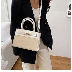 Detail view of stylish white leather and straw woven handbag worn with a black blazer
