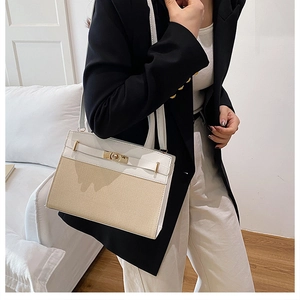 Detail view of contrast stitch shoulder bag with woven texture and gold hardware lock