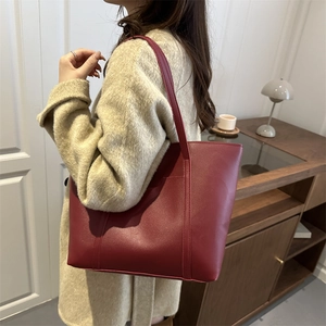 Deep red large PU leather tote bag with long handles styled on shoulder with wool coat