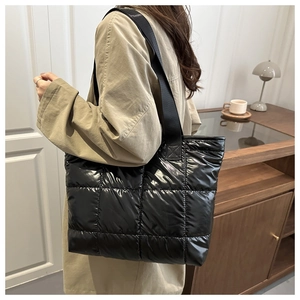 Detail of black quilted puffer tote bag in glossy nylon fabric with thick strap