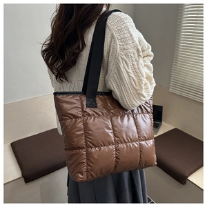 Macro detail of brown quilted down tote bag showing glossy texture and shoulder strap