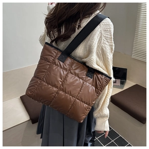 Detailed view of quilted coffee brown tote bag with glossy finish and black strap