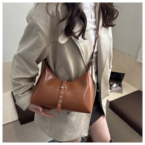 Dettaglio borsa a spalla in pelle caramello con rivetti argento su modella in blazer