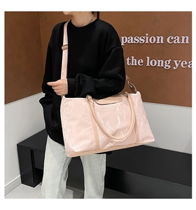 Dettaglio della trama di una grande borsa da viaggio rosa con tracolla e manici regolabili