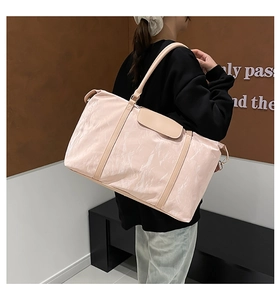 Detail of light pink travel bag showing crinkle nylon texture and metal D-ring hook