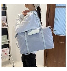 Borsa da viaggio in nylon azzurro indossata da una modella con tracolla regolabile