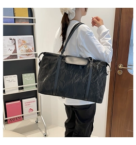 Close-up of large black travel bag with crinkled texture fabric on a model