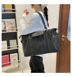 Dettaglio di borsa da viaggio nera testurizzata con manici e anelli metallici