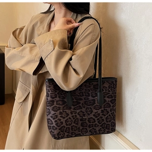 Detailed view of leopard print tote bag with black straps on a trench coat model