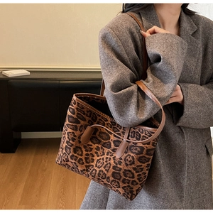 Detailed side view of leopard print tote bag with brown leather straps on wool coat