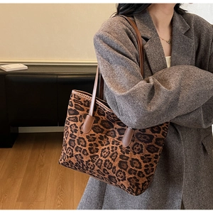 Detail view of a stylish leopard print tote bag with brown leather handles and a large capacity