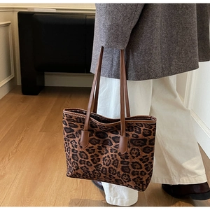 Detailed close-up of a leopard print tote bag with brown leather handles for women