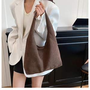 Detail of soft dark brown suede tote bag carried by model in an urban office setting