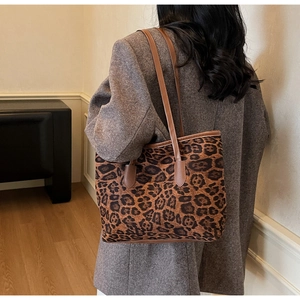 Detail of trendy leopard print tote bag with brown straps worn on a grey wool coat