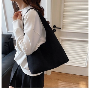 Lifestyle view of large black minimalist tote bag worn by model with white sweatshirt