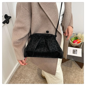 Detail of black leopard print crossbody bag with velvet texture on beige wool coat