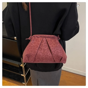 Detailed back view of a burgundy leopard print pleated crossbody bag worn by a model