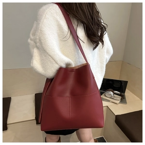 Detailed view of a red large leather tote bag worn over the shoulder for winter fashion
