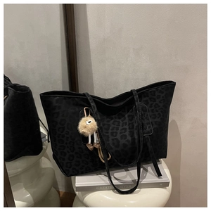 Detail of black leopard canvas tote bag with slim shoulder strap and plush charm