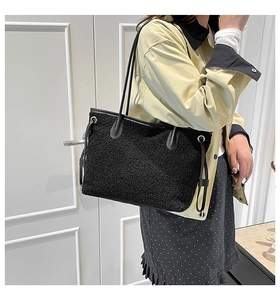 Detail of black plush tote bag with drawstring accents and leather-like handles on model