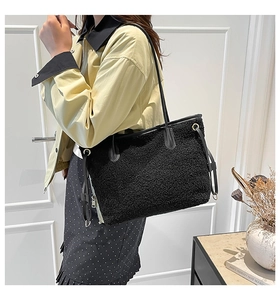 Close-up of black fleece tote bag featuring leather handles and metal zipper detail