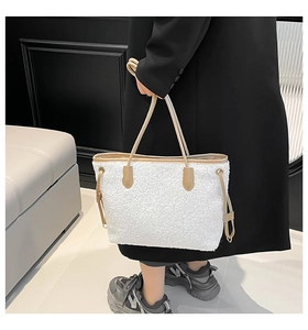 Close-up of white plush tote bag with khaki leather handles and side drawstring detail