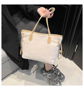 Close-up of fluffy off-white faux shearling tote bag with beige leather handles