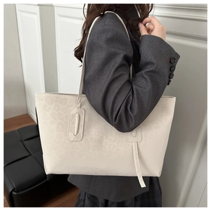 Detailed view of off-white tote bag with leopard texture on gray blazer outfit