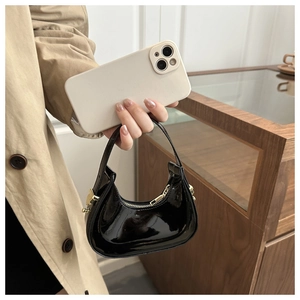 Mini black patent leather hobo bag size comparison with a smartphone on casual outfit