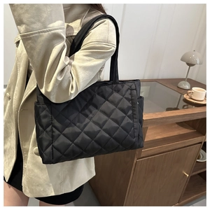 Detail of black quilted nylon tote bag showing diamond texture and side pocket
