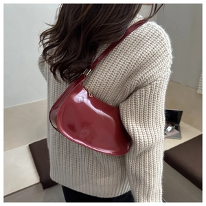 Detail showing high-gloss patent leather texture and sleek curved design of the burgundy bag