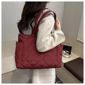 Close-up of wine red quilted tote bag featuring a side pocket and lightweight nylon texture